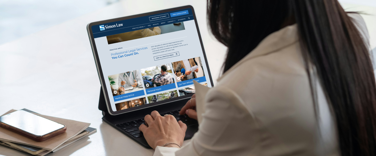 A woman in a white blazer works on a tablet displaying a legal services website. The scene conveys a professional and focused atmosphere.